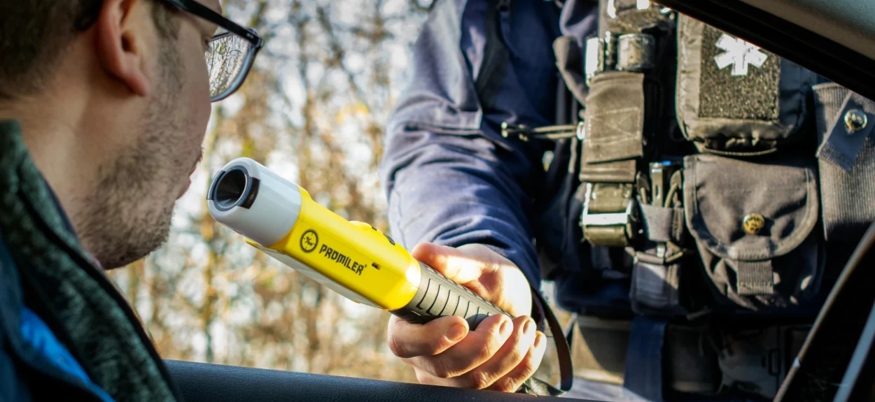 Policajac koji vrši alkotest nad licem koje upravlja vozilom.