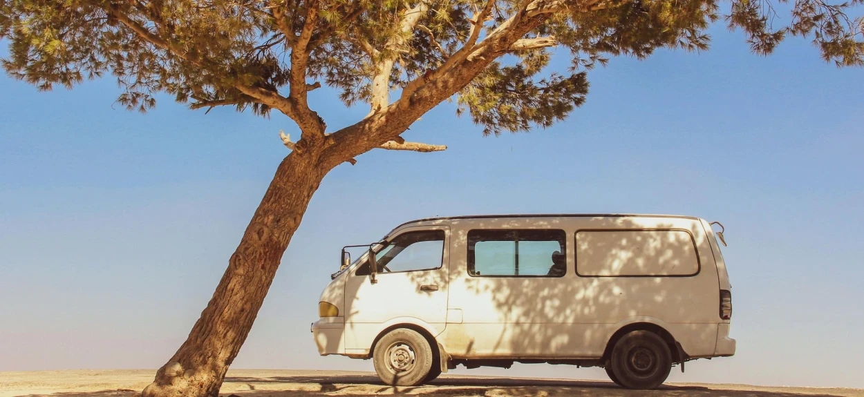 Automobil parkiran u hladu ispod drveta tokom letnjeg dana – primer prevencije pregrevanja i rizika od požara