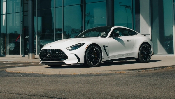 Beli auotomobil marke Mercedes parkiran ispred zgrade.