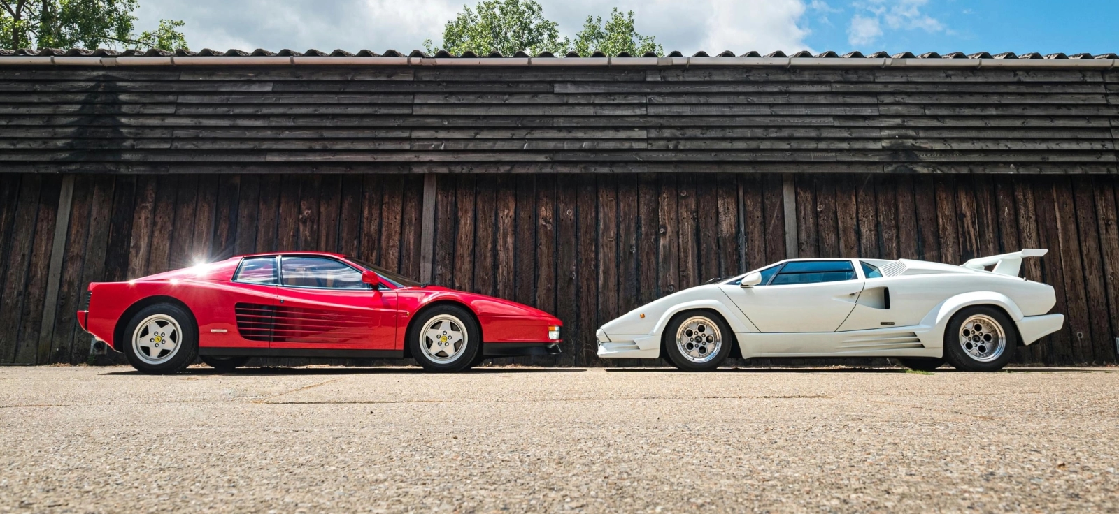 Direktan okršaj titana: Crveni Ferrari Testarossa i beli Lamborghini Countach parkirani jedan pored drugog kao simbol večitog rivalstva