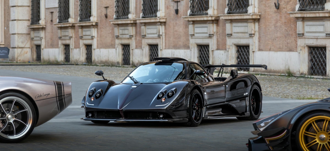 Crni Pagani hiperautomobil ispred klasične arhitekture, prikazuje upotrebu karbona nastalu iz rivalstva sa Lamborghinijem