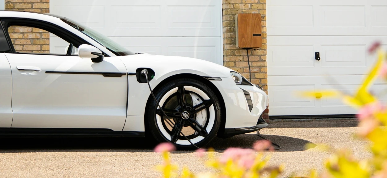 Električni automobil koji se puni ispred kuće pomoću kućnog punjača – moderna infrastruktura za punjenje EV vozila