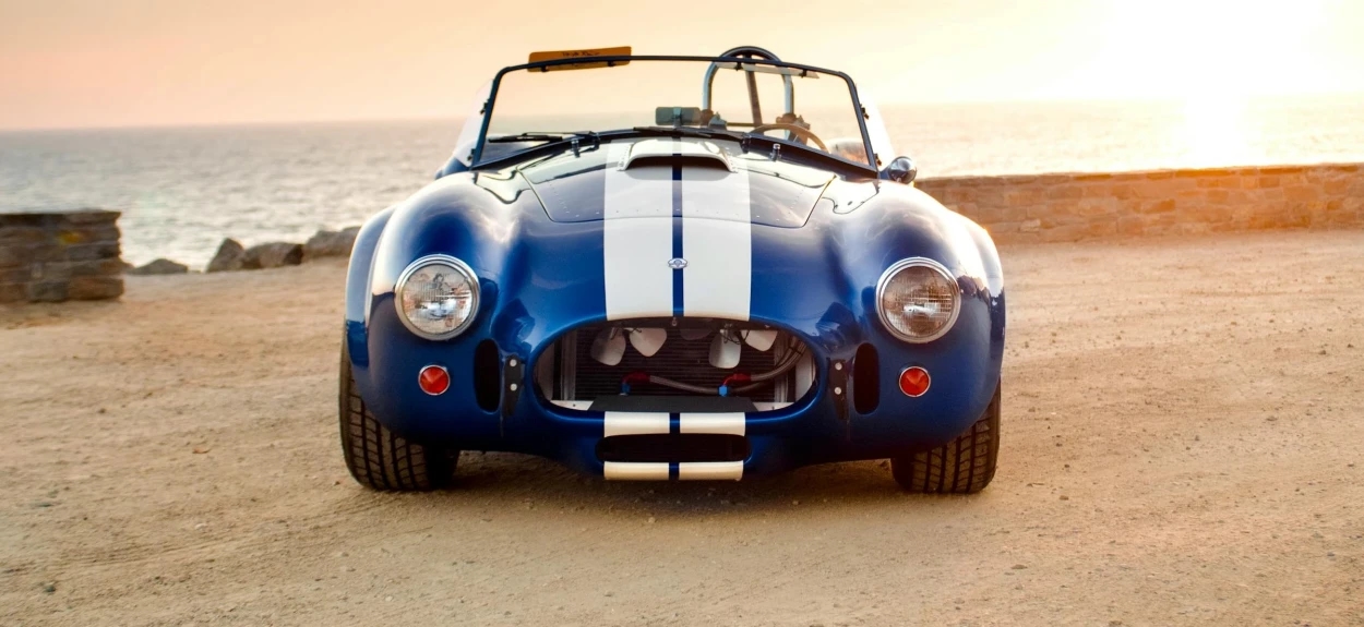 Frontalni pogled na Shelby Cobra 427 na obali u zalazak sunca, prepoznatljivi sportski automobil sa Ford 427 V8 motorom