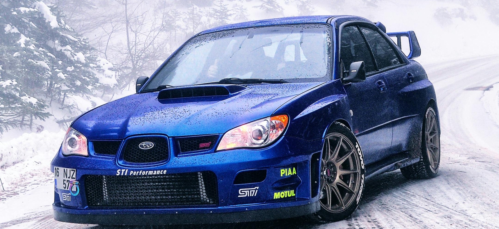 Plavi Subaru WRX STI na snežnom putu, demonstracija stabilnosti i superiornosti simetričnog AWD sistema u ekstremnim zimskim uslovima.