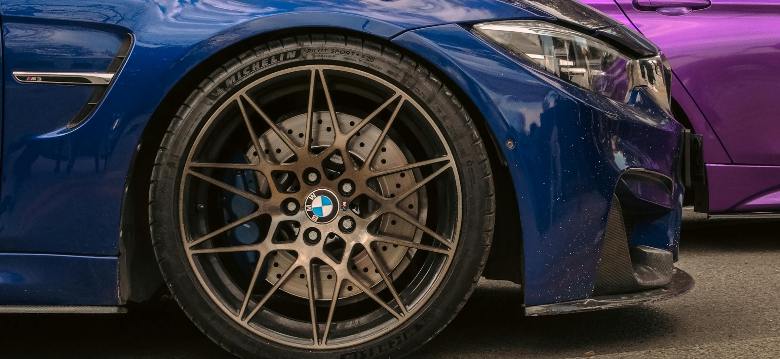 Bliski prikaz sportske višezvzdane aluminijumske felne sa niskoprofilnom letnjom gumom na plavom automobilu