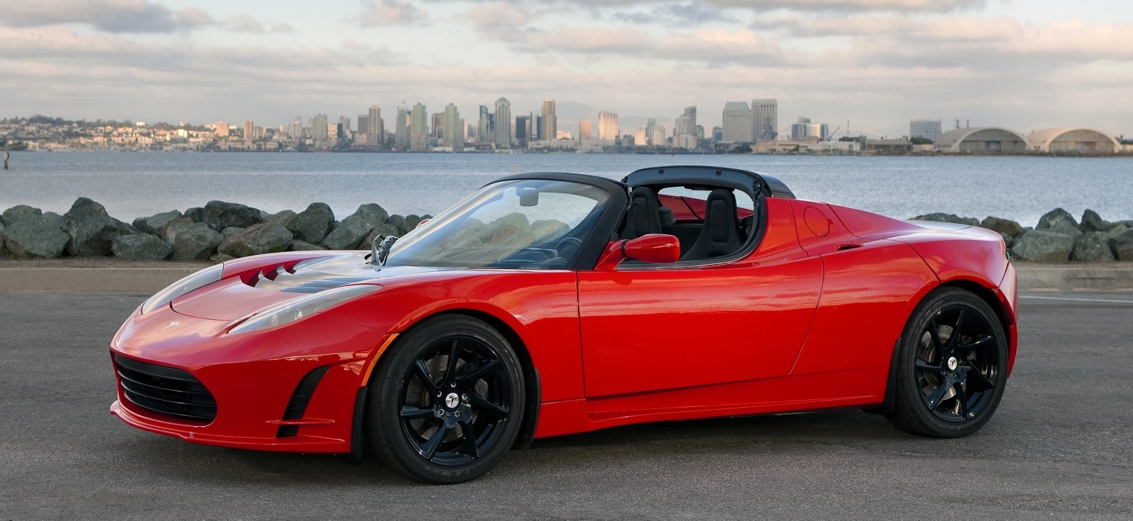 Tesla Roadster 2008 parkiran pored obale u San Dijegu sa panoramom grada