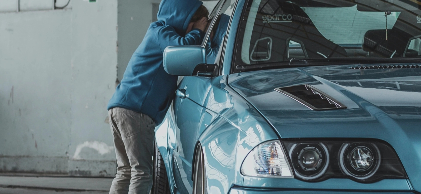 Dete u plavom duksu gleda kroz auto kako bi videlo njegovu unutrašnjost.