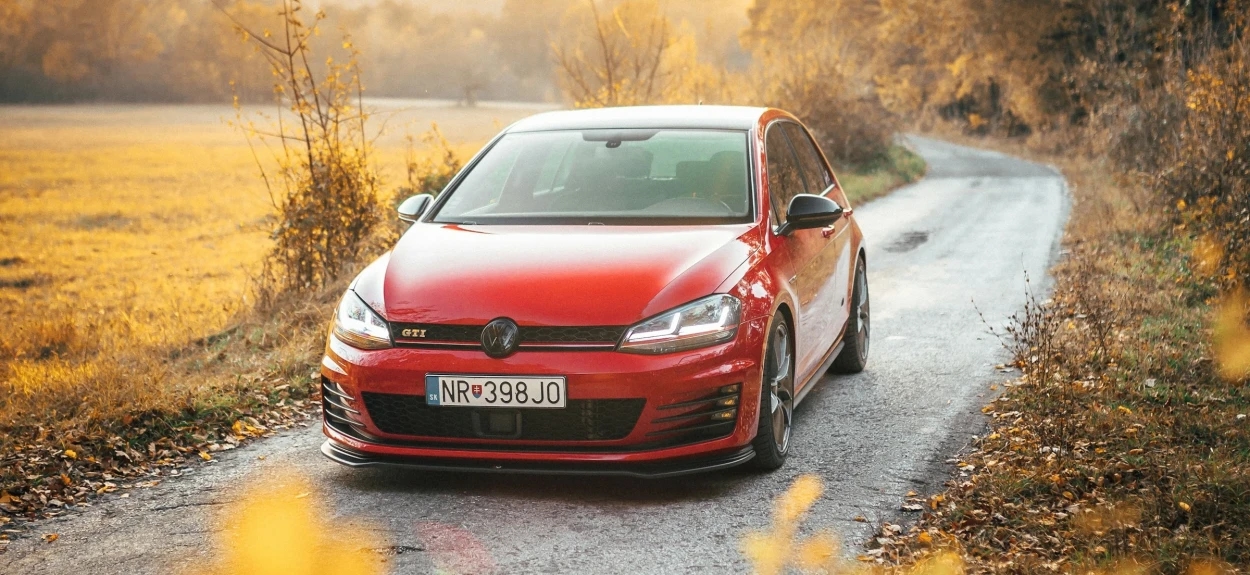 Crveni Volkswagen Golf GTI Mk7 na seoskom putu tokom jeseni – simbol spoja svakodnevne upotrebe i sportskog karaktera.