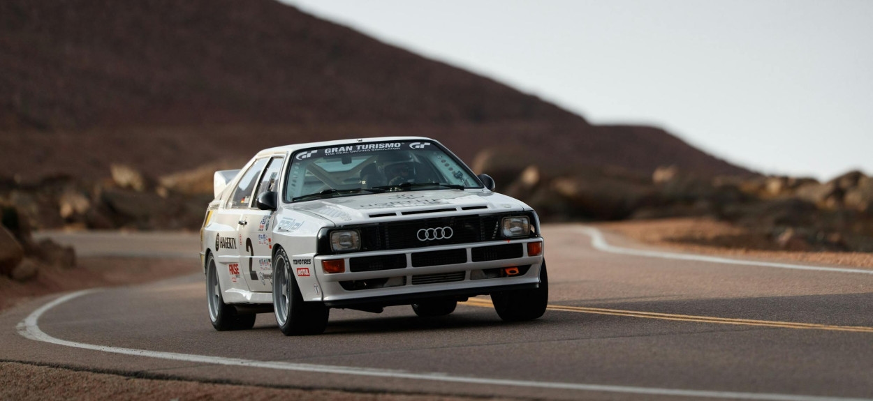 Beli Audi Sport Quattro S1 u vožnji na planinskom putu, legendarni reli automobil Grupe B sa proširenim rubovima