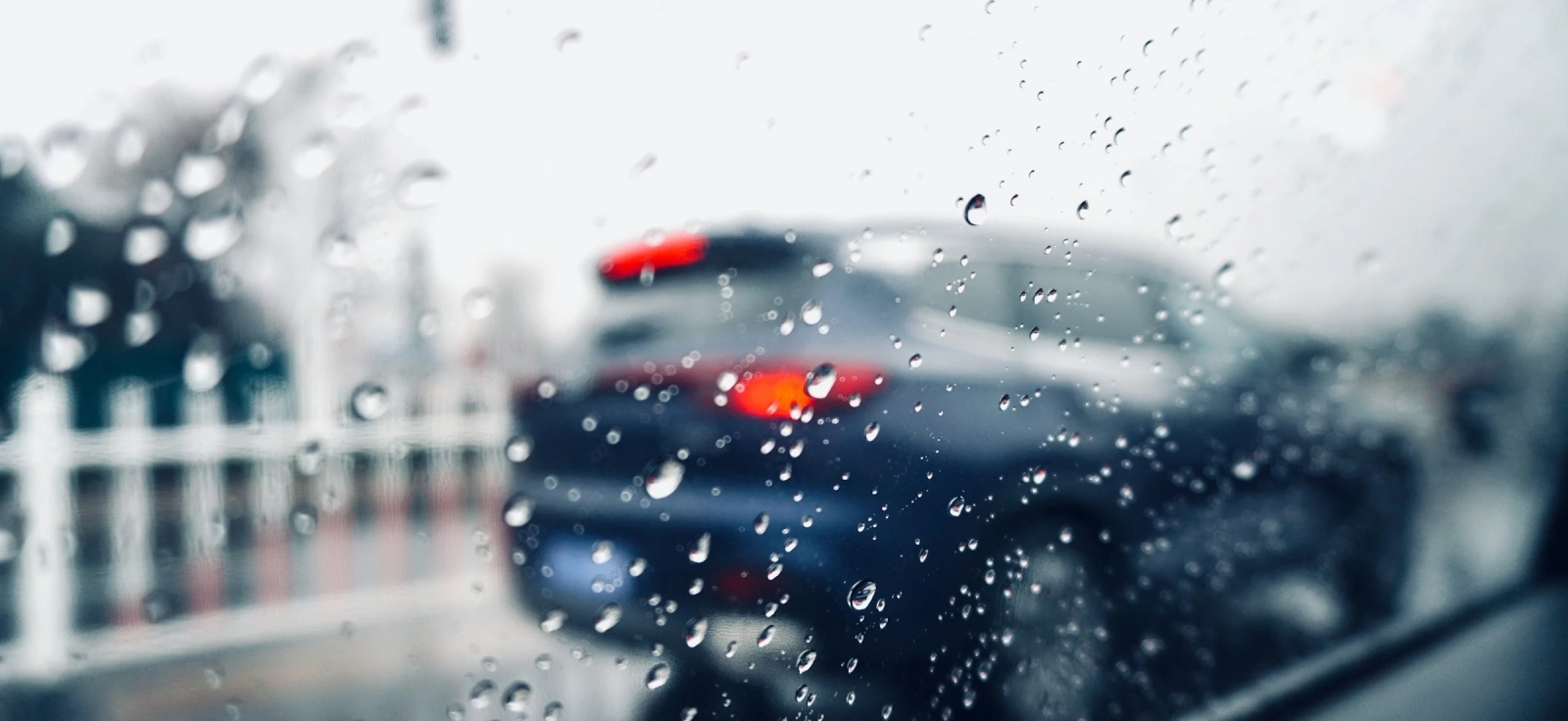 Pogled kroz zamagljenu šoferku tokom kiše – automobil u saobraćaju i kapljice vode na staklu