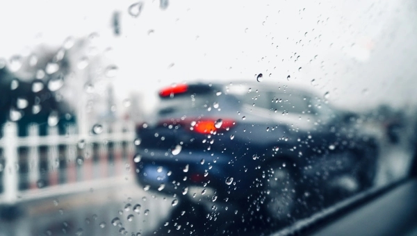 Pogled kroz zamagljenu šoferku tokom kiše – automobil u saobraćaju i kapljice vode na staklu