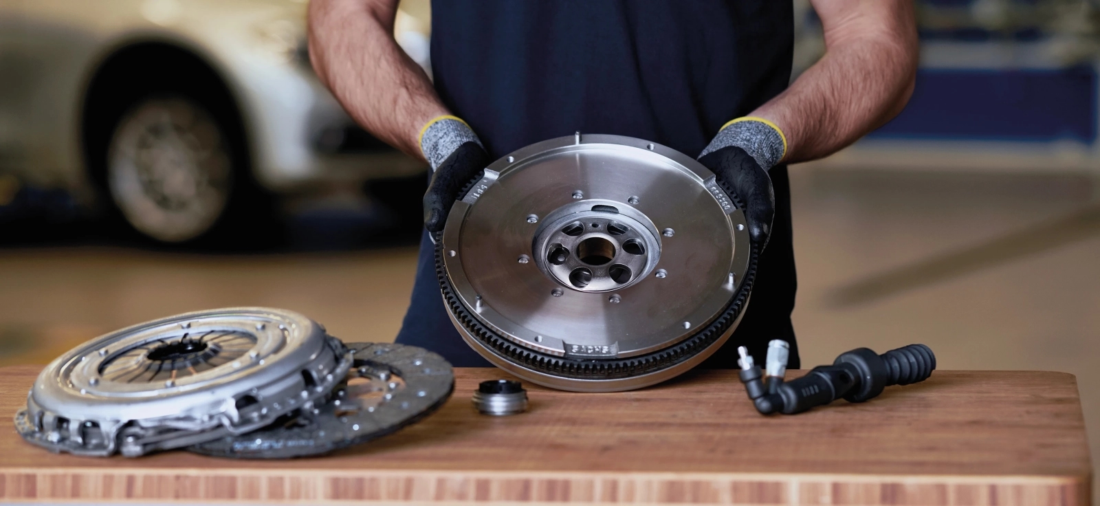 Mehaničar drži plivajući dvomaseni zamajac tokom servisa automobila u radionici