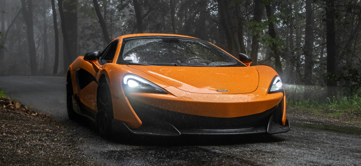 Narandžasti automobil McLaren u sumi na putu.