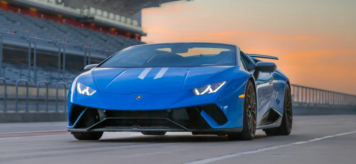 Plavi Lamborghini na trkačkoj stazi za vreme zalaska sunca.